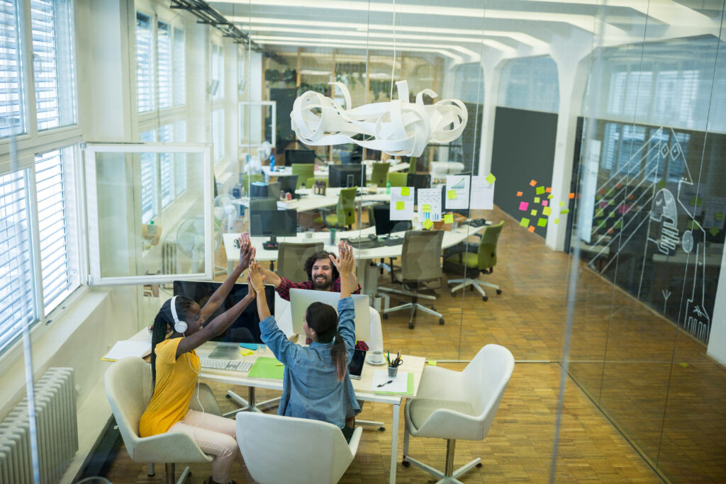 Group of graphic designers giving high five to each other in office